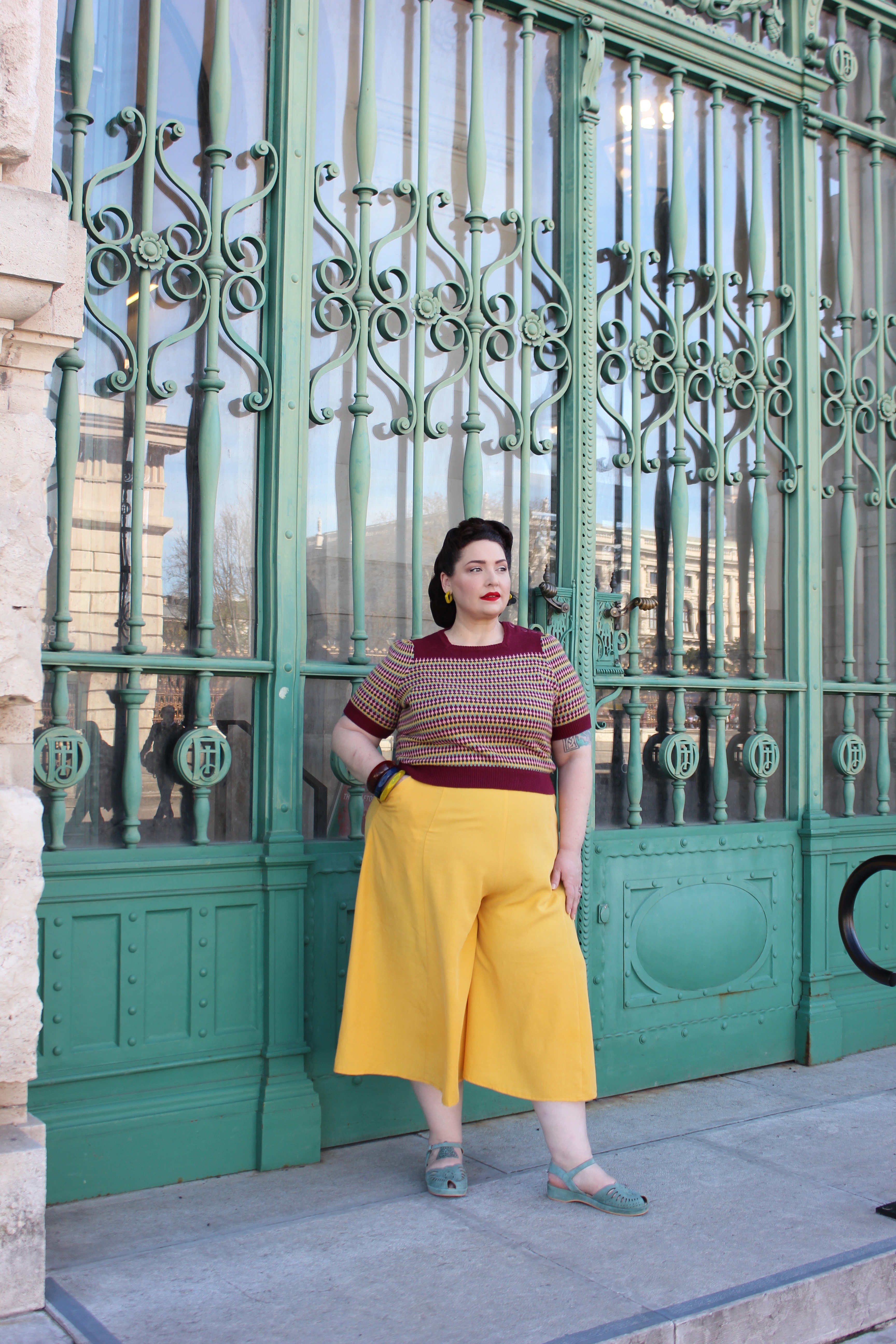 Full outfit view of plus-size vintage spring look with culottes and knit top on a sunny day in Vienna